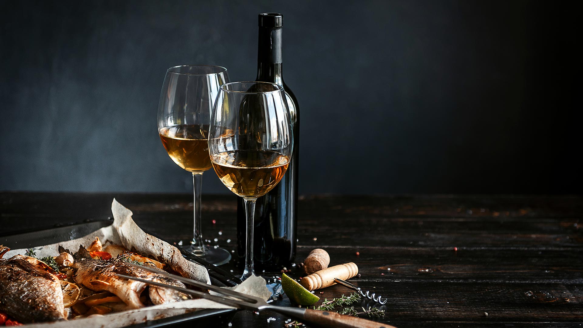 Botella de vino con copas y plato de pescado asado, representando la experiencia gastronómica en Alcrique, restaurante en Pontevedra.