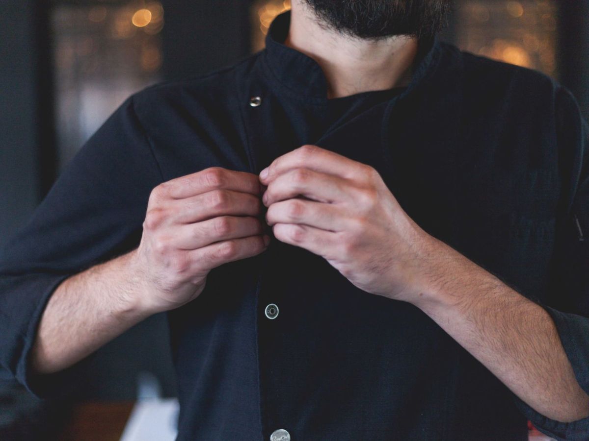 Chef ajustando su chaqueta en la cocina de Alcrique, restaurante en Pontevedra, reflejando dedicación y pasión por la gastronomía.